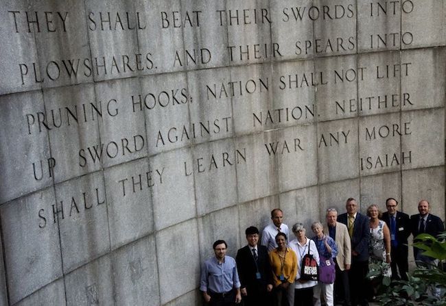  Faith groups' representatives in front of the Isaiah Wall across the street from the United Nations Building in New York City with the Bible verse "...they shall beat their swords into plowshares, and their spears into pruning hooks: Nation shall not lift up sword against nation, neither shall they learn war any more." Credit: ICAN