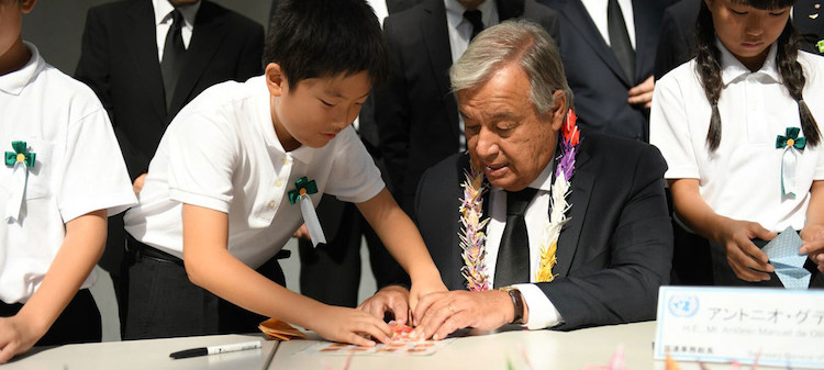 Photo: Secretary-General António Guterres folds origami cranes with young Japanese leaders at the Nagasaki Peace Memorial. Credit: Dan Powell | UN Photo.